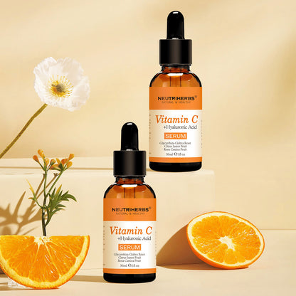 Neutriherbs Vitamin C + Hyaluronic Acid Serum 30 ml juntamente com laranjas frescas e flores. Imagem de produto inspiradora que destaca o conteúdo de vitamina C do sérum para pele hidratada, maior luminosidade e um tom de pele mais uniforme.